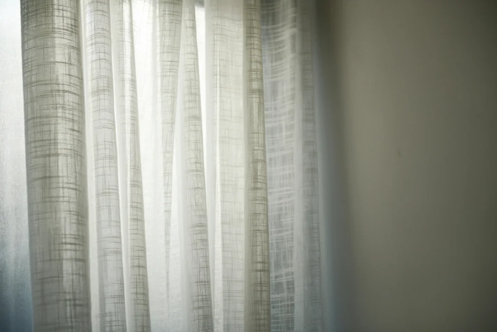 sunlight filtering through some white sheer curtains